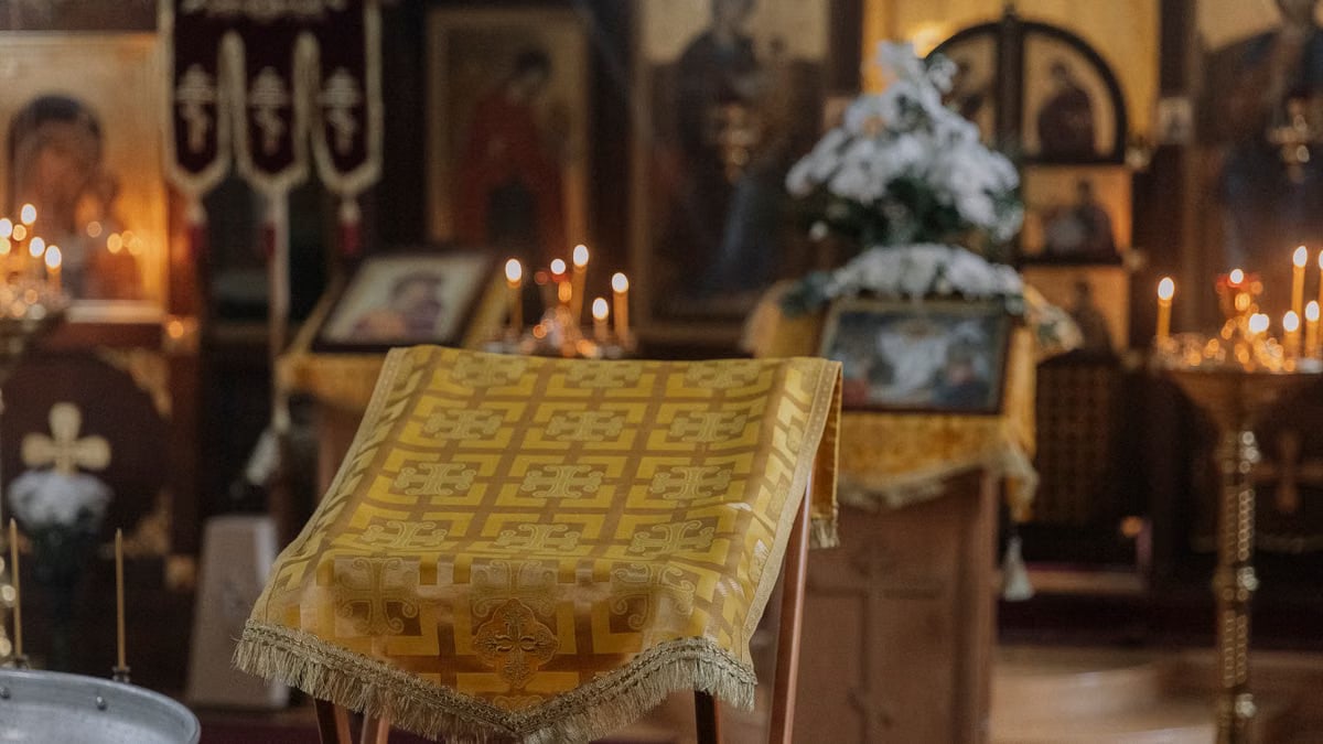 Ornate church interior with candles, lectern, and religious icons creating a serene atmosphere.
